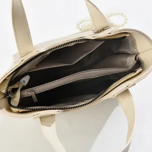Détail du sac à main en cuir PU crème avec intérieur multicouche et charme perlé