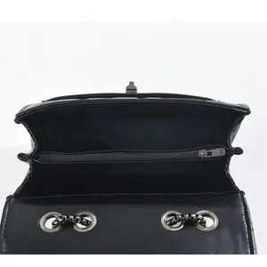 Internal view of black quilted flap handbag with dual compartments and silver chain eyelets