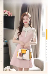 Detail of color-block handbag with pink fur pom pom charm and lace dress