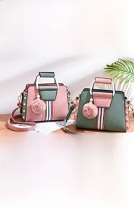 Detail of color-block leather handbags with pearl rivets and pink pom-pom keychain