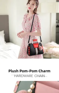 Close-up of contrast color handbag hardware with plush ball charm and striped ribbon