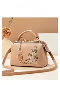 Detailed close-up of floral embroidery on a beige handbag with gold hardware