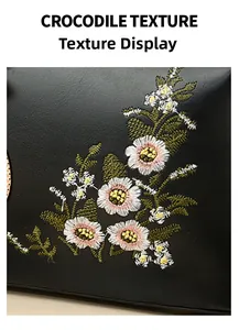Detail of floral embroidery on black crocodile texture leather handbag surface