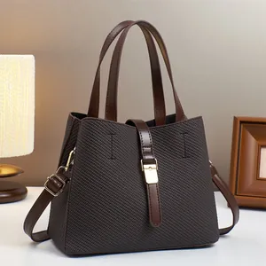 Detail of a brown woven texture bucket bag with gold hardware and dual handles
