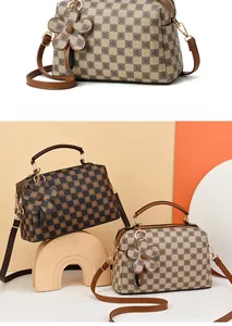 Checkerboard pattern crossbody bag detail showing leather flower charm and top handles