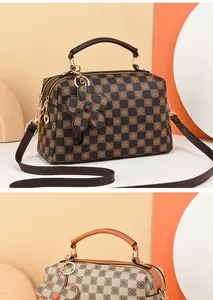 Detail of checkered Boston bags with double handles and flower charms in brown and white