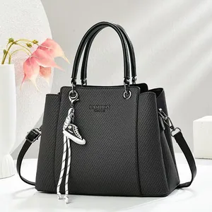 Elegant black textured crossbody handbag for women featuring a stylish sneaker charm