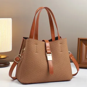 Detail of caramel woven texture bucket bag with metal buckle and leather strap handles