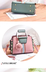 Detail of color-block handbag base with metal feet and pearl accents on pink leather