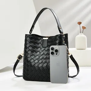 Grand sac seau tressé noir avec poignée supérieure et bandoulière montrant l'échelle réelle