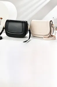 Detail of minimalist saddle bags in black and beige with elegant stitching and golden hardware