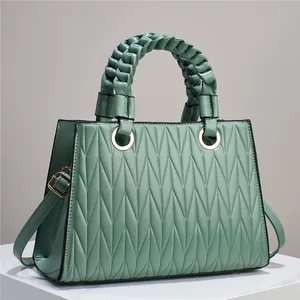 Detail of sage green quilted handbag with woven handle and gold ring hardware