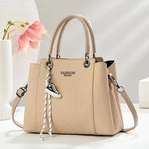 Detail view of khaki textured leather handbag featuring Fashion Queen print and sneaker charm
