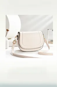 Detail of cream saddle bag featuring U-shaped stitching and golden hardware accents