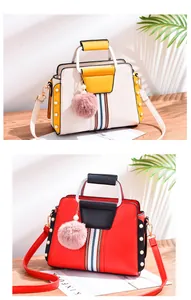 Detail of stylish color-block handbags with pearl studs and pink fur pompom charms