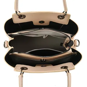 Vertical view of a beige handbag interior with three compartments and metal hardware