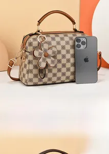 Detail view of plaid patterned handbag with floral accents and brown leather handle