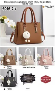 Detailed view of women's embossed leather handbag with pompom charm and multi-color options