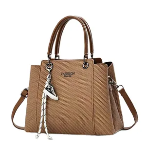 Brown fabric textured tote bag with top handles, crossbody strap and a sneaker charm