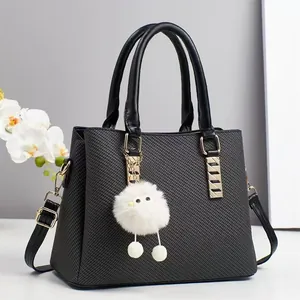 Elegant black woven texture tote bag with gold hardware and white plush charm