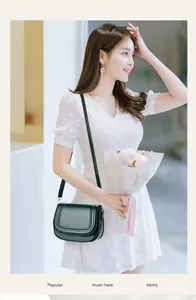 Close-up of deep green leather saddle bag with flap closure on floral dress model
