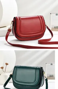Detail of red and dark green saddle bags with minimalist leather texture and gold hardware