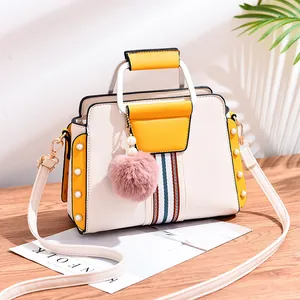 Contrast color handbag in cream and yellow with pearl details and a pink fur ball charm