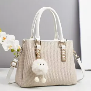 Close-up of beige woven texture handbag with white leather handles and plush charm accessory