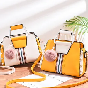 Two-tone crossbody handbag in cream and yellow with chic fuzzy ball charm accessory