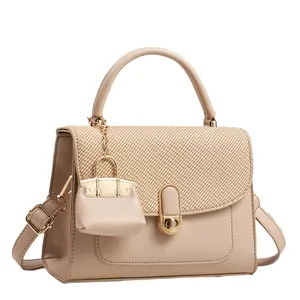 Sac bandoulière beige minimaliste avec rabat tressé et poignée ronde sur fond blanc