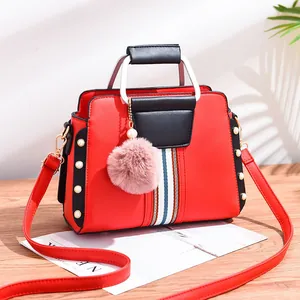 Contrast color red and black PU leather handbag with elegant pearl rivets and fur ball charm