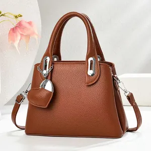 Brown litchi grain bucket bag with silver heart charm and crossbody strap shown in a 45-degree view