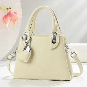 Close-up of lychee textured cream bucket bag with heart charm and silver hardware