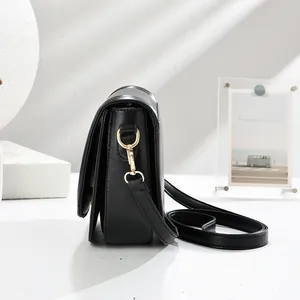 Minimalist black leather saddle bag with gold metal D-ring and elegant side profile