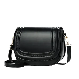 Minimalist black saddle crossbody bag with leather texture and flap indentation detail