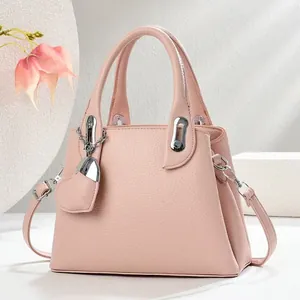 Detail of pink lychee leather bucket bag with silver hardware and heart pendant charm