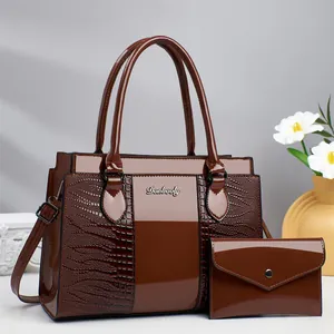 Detail of dark brown crocodile pattern handbag set with glossy finish and metal logo
