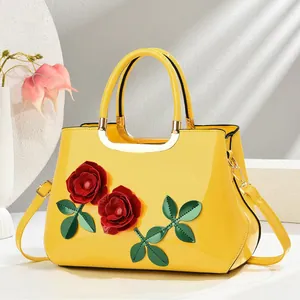 Détail du sac à main en cuir verni jaune avec roses 3D rouges et garnitures dorées
