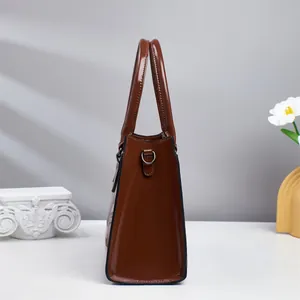 Detail view of glossy brown croc-embossed tote bag with elegant metallic ring hardware