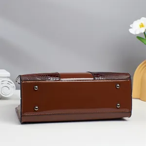 Detail of dark brown faux crocodile handbag base with metal protective feet and stitching