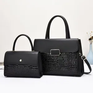 Detail of black tote set featuring smooth leather and crocodile texture with metal buckle