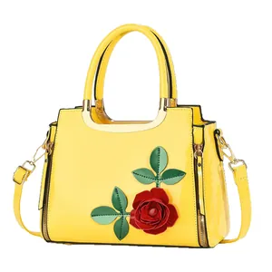 Sac à main élégant en cuir verni jaune avec appliqué floral et poignées dorées