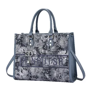 Blue tote bag with letter embroidery and cloud patterns on a clean white background