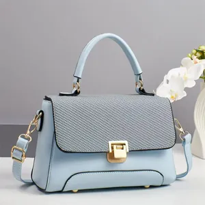 Detailed view of pastel blue handbag with grey woven flap and golden twist lock closure