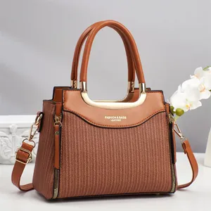 Sac à main marron avec texture tissée, poignées en cuir et détails métalliques dorés