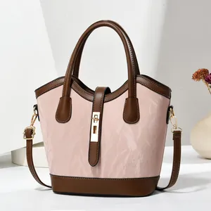 Vue détaillée du sac cabas rose avec anses brunes, fermoir doré et texture de cuir