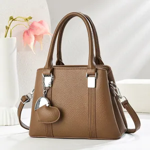 Gros plan d'un sac à main marron texturé avec pendentif coeur et doubles anses