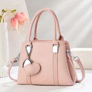 Détail du sac coquille en cuir rose clair avec breloque cœur et bandoulière chaîne