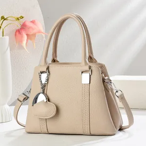 Sac à main beige élégant avec texture cuir grainé et pendentif en forme de cœur