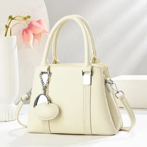 Gros plan du sac coquillage en cuir litchi beige avec ferrures argentées et pendentif